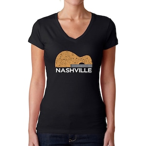 Puede incluir: Camiseta negra de cuello en V con un gr&aacute;fico de una silueta de guitarra compuesta por palabras relacionadas con Nashville, Tennessee. Las palabras son de color naranja y la guitarra est&aacute; delineada en gris. El texto "NASHVILLE" est&aacute; impreso en blanco debajo de la guitarra.