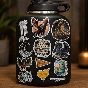 May include: Black water bottle covered in fantasy-themed stickers. Stickers include a dragon rider, a dragon reading a book, a crescent moon, and the text "Books Saved My Life". Other stickers have the text "Well the F*ck Aware" and "Xaddy".