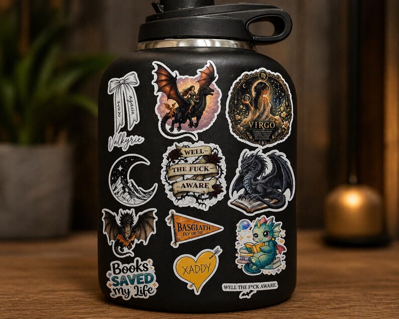 May include: Black water bottle covered in fantasy-themed stickers. Stickers include a dragon rider, a dragon reading a book, a crescent moon, and the text "Books Saved My Life". Other stickers have the text "Well the F*ck Aware" and "Xaddy".