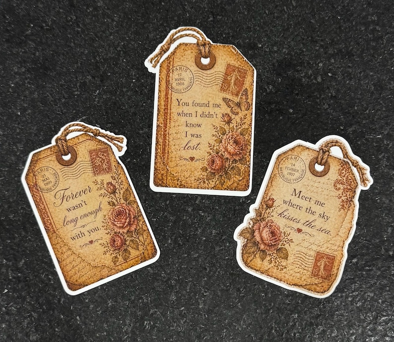 May include: Three vintage-style gift tags with romantic quotes and floral accents. Each tag features a distressed paper design, postage stamps, and a twine loop for hanging. The tags have quotes like "Forever wasn't long enough with you."
