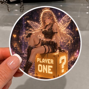K&ouml;nnte beinhalten: Ein runder Aufkleber mit einem Fantasy-Anime-Charakter mit Feenfl&uuml;geln, der auf einem leuchtenden goldenen Block mit den Worten "PLAYER ONE" und einem Fragezeichen sitzt. Der Charakter hat lange Haare und tr&auml;gt ein dunkles Outfit.