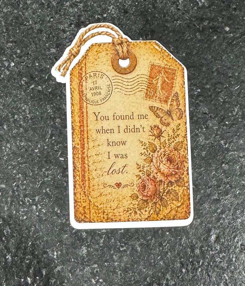 May include: A vintage-style gift tag with a distressed, sepia-toned design. The tag features floral and butterfly illustrations, along with the text "You found me when I didn't know I was lost." A twine loop is attached.