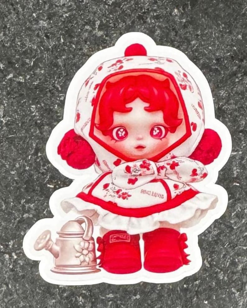 K&ouml;nnte beinhalten: Ein Aufkleber mit einer puppenartigen Figur mit roten Haaren und passendem Outfit. Die Figur tr&auml;gt ein wei&szlig;es Kleid mit roten Blumenmustern und einer passenden Kapuze. Eine kleine Gie&szlig;kanne ist ebenfalls im Design enthalten.