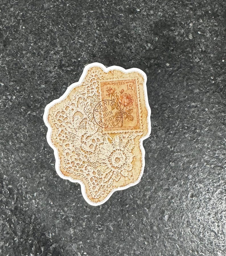 Op de afbeelding: Een vintage sticker met een cr&egrave;mekleurig kantpatroon en een postzegelontwerp. De postzegel toont een roos en de tekst "Postes" en "Paris 18 Juin 1907". De sticker heeft een witte rand.