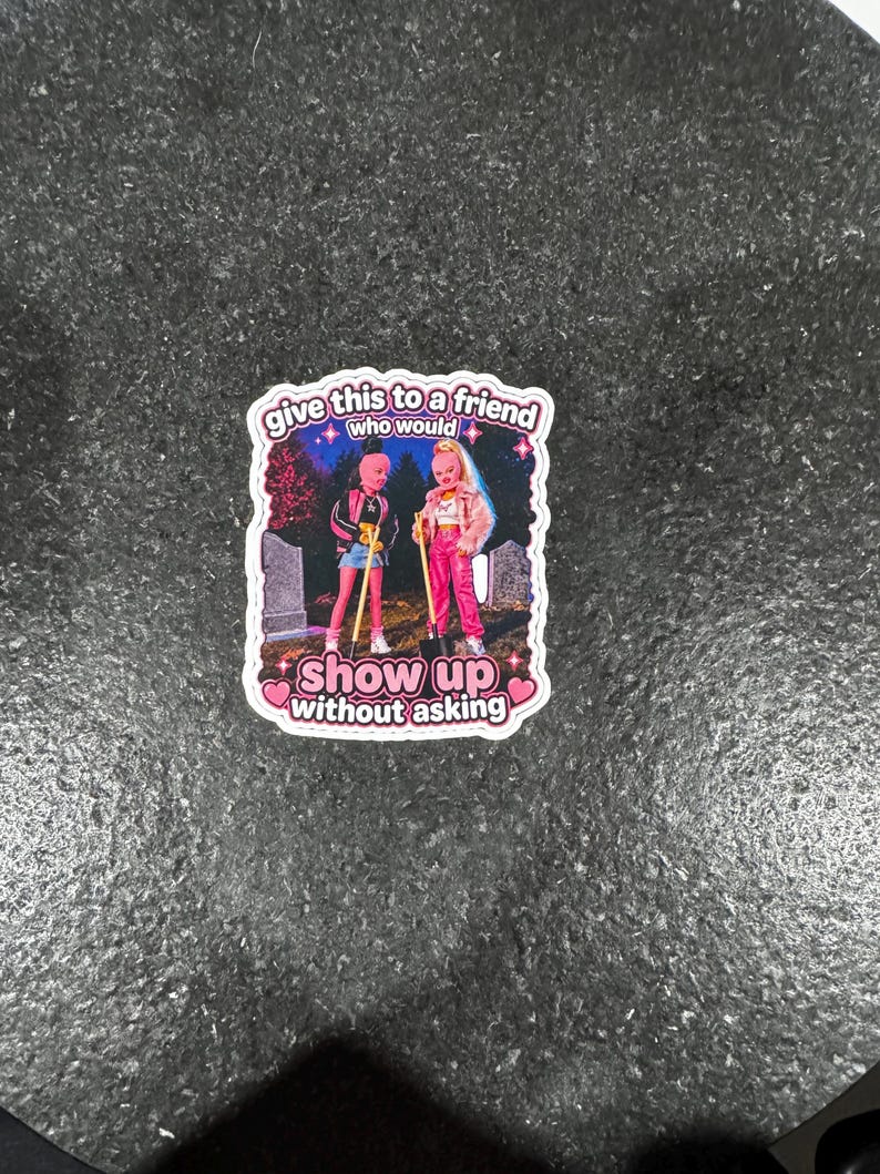 May include: A sticker featuring two cartoon figures standing in front of a graveyard. The text on the sticker reads "give this to a friend who would show up without asking."