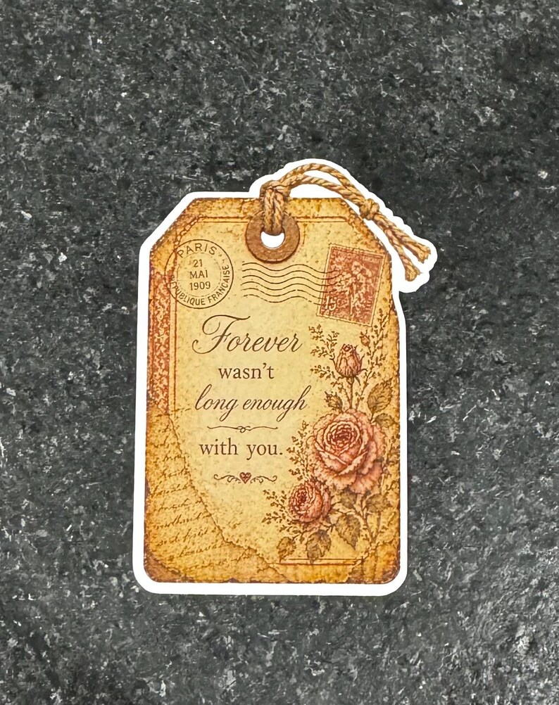 May include: A vintage-style gift tag with a brown paper texture, featuring the text "Forever wasn't long enough with you." It includes a floral design with roses and a postage stamp illustration. A twine loop is attached.