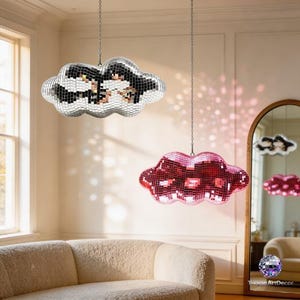 May include: Two cloud-shaped disco ball pendant lights hanging from the ceiling. One is silver, the other is red. The lights are suspended by chains and reflect light, creating a sparkling effect. The room has a neutral color palette.