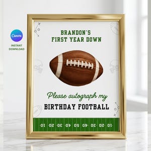 Op de afbeelding: Een goudkleurig ingelijst bord met een afbeelding van een bruine American football met witte veters. De tekst luidt: BRANDON'S FIRST YEAR DOWN, Please autograph my BIRTHDAY FOOTBALL, met onderaan een grafische weergave van een veld.