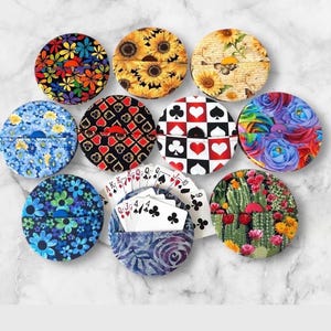 May include: A collection of round fabric card holders with various floral, sunflower, and playing card designs. One holder contains a deck of playing cards. The holders are in shades of blue, yellow, red, and green.