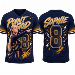 Pode incluir: Uma t-shirt azul-marinho com decote em V apresentando o gráfico de uma jogadora de basquete apontando, o texto "POINT GOD" em amarelo e o número "8". As costas exibem o nome "SOPHIE" em amarelo sobre um grande número "8" com detalhes de raios e estrelas.