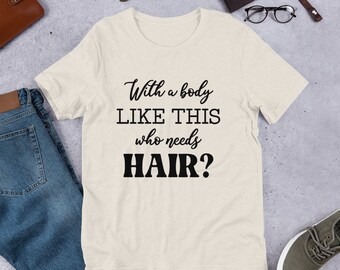 May include: A beige t-shirt with the text "With a body like this who needs hair?" printed in black.