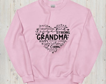 May include: Pink sweatshirt with a black heart design that says "Giving, Inspiring, Wise, Devoted, Kind, Strong, Grandma, Happy, Loving, Generous, Caring, Loving, Kind".