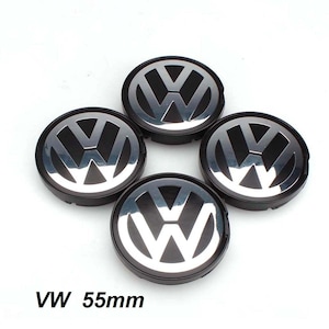 May include: Four black and silver VW wheel center caps. Each cap features the VW logo in silver against a black background. The text "VW 55mm" is visible at the bottom of the image.