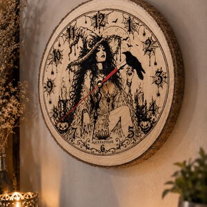 Pu&ograve; includere: Un orologio da parete rotondo realizzato con una fetta di legno naturale con bordi in corteccia. Il quadrante presenta un'illustrazione a inchiostro nero di una strega con un corvo, candele, zucche e ragnatele. Ha lancette nere e una rossa.