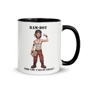 May include: White ceramic mug with a black interior and handle. The mug features a cartoon illustration of a muscular character with the text "RAM-BOT" and "WHO YOU CALLIN SMALL?" printed on it. The character is flexing his bicep.