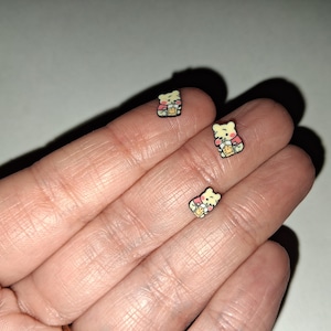 Puede incluir: Un letrero de madera hecho a mano con la palabra "Bienvenido" en una fuente juguetona. El letrero está pintado de blanco con un acabado envejecido y presenta un diseño floral en tonos rosas y verdes. Mide aproximadamente 30 cm de ancho.