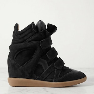 May include: Black high-top wedge sneakers with three hook-and-loop straps and a tan sole. The sneakers have a suede upper and a leather accent on the toe. The design features a hidden wedge heel.