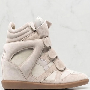 以下が含まれることがあります： ベージュのハイカットスニーカー、ウェッジヒール付き。 スエードとレザーのアッパー、面ファスナー、ラバーソールが特徴です。 デザインには、カットアウトのディテールとパッド入りの襟が含まれています。