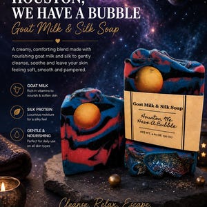 May include: Two bars of Goat Milk & Silk Soap with red, blue, and black swirls, and a gold sphere. The soap is labeled "Houston, We Have a Bubble." The image includes text about the soap's benefits and ingredients.