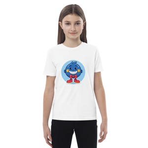 May include: White t-shirt with a cartoon blueberry character design. The blueberry has a smiling face, red bow tie, and red shoes, set on a blue circle. The shirt is worn by a person.