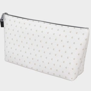 Puede incluir: Un estuche rectangular con cremallera en color blanco con un patrón repetitivo de pequeños puntos de color beige claro. El accesorio cuenta con un cierre de cremallera de metal plateado en el borde superior y una pequeña etiqueta de tela negra.