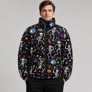 Può includere: Un piumino nero con una stampa colorata all-over di scheletri danzanti con cuffie, palle da discoteca, stelle, note musicali e zucche. La giacca presenta un colletto alto, una chiusura con zip frontale a tutta lunghezza e maniche lunghe.