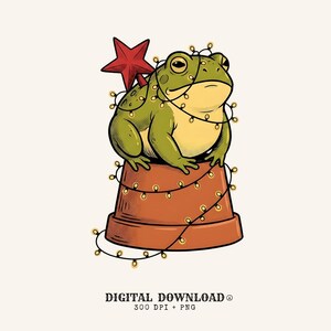 May include: A green frog sits atop an inverted terracotta-colored flower pot, wrapped in a string of glowing yellow fairy lights. A large, five-pointed red star is positioned behind the frog. Text below reads: DIGITAL DOWNLOAD 300 DPI + PNG.