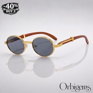 May include: Round sunglasses featuring gold-tone metal frames with dark grey lenses and brown wooden temples. The glasses include a small badge in the upper left corner with the text -40% BUY 2 and the brand name Orbigems in the bottom right corner.