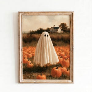 Puede incluir: Una impresión de arte mural enmarcada que representa a un fantasma blanco cubierto con una sábana en un campo de calabazas naranjas. Al fondo, una casa de dos pisos se alza bajo un cielo nublado. Numerosas calabazas de varios tamaños cubren el suelo.