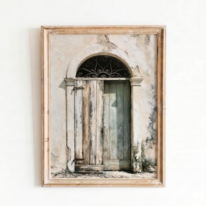 Puede incluir: Obra de arte enmarcada que representa una puerta de madera desgastada con una ventana arqueada de hierro forjado. La puerta está pintada en tonos azules y marrones, sobre una pared texturizada de color blanquecino. El marco es de color marrón claro.