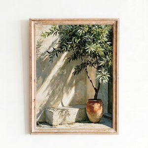 Puede incluir: Pintura enmarcada que representa un olivo en maceta de terracota. El árbol tiene hojas y aceitunas verdes. El fondo presenta una pared texturizada con sombras y un escalón de piedra. El marco es de color marrón claro.