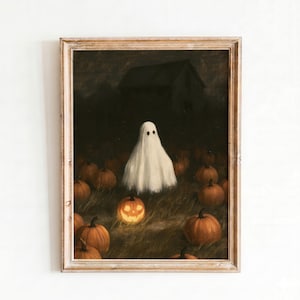Puede incluir: Una impresión artística enmarcada que representa a un fantasma blanco de pie en un campo oscuro lleno de calabazas naranjas por la noche. Una calabaza central está tallada con una cara brillante, con la silueta oscura de una casa al fondo.