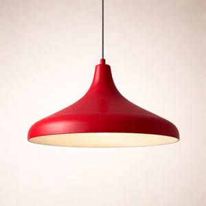 May include: A red pendant light fixture with a wide, flared shade. The light hangs from a black cord and has a white interior. The fixture is a bright, solid red color and is designed to be suspended from the ceiling.