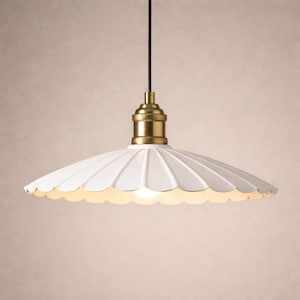 Puede incluir: Lámpara colgante blanca con borde festoneado, accesorio de latón y cable negro. La lámpara tiene un borde decorativo festoneado y un brillo cálido. El diseño recuerda a los estilos vintage o rústicos.