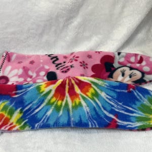 May include: Two fleece slipper socks. One is pink with a Minnie Mouse design and the word "Minnie". The other is a tie-dye pattern in blue, red, yellow, and green.