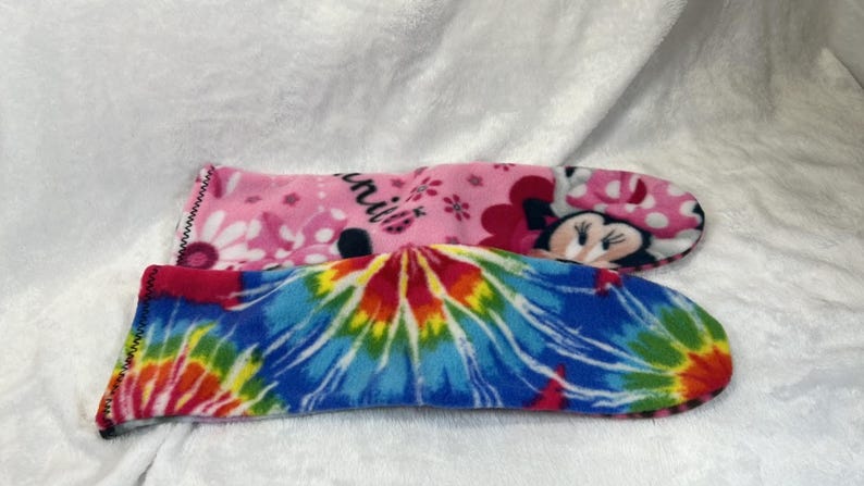 May include: Two fleece slipper socks. One is pink with a Minnie Mouse design and the word "Minnie". The other is a tie-dye pattern in blue, red, yellow, and green.