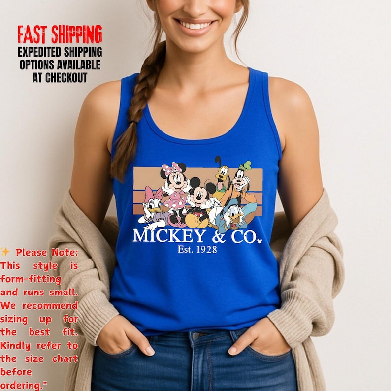 Puede incluir: Una camiseta sin mangas azul real con un gr&aacute;fico de Mickey Mouse y sus amigos. El gr&aacute;fico incluye a Mickey, Minnie, Donald, Daisy, Goofy y Pluto, con el texto "MICKEY & CO. Est. 1928". La camiseta tiene cuello redondo y la lleva una persona.