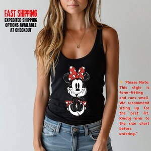 May include: Black tank top featuring a Minnie Mouse graphic with a red and white polka dot bow. The tank top has a scoop neck and is paired with blue jeans. Text on the image reads "FAST SHIPPING" and "EXPEDITED SHIPPING OPTIONS AVAILABLE AT CHECKOUT."
