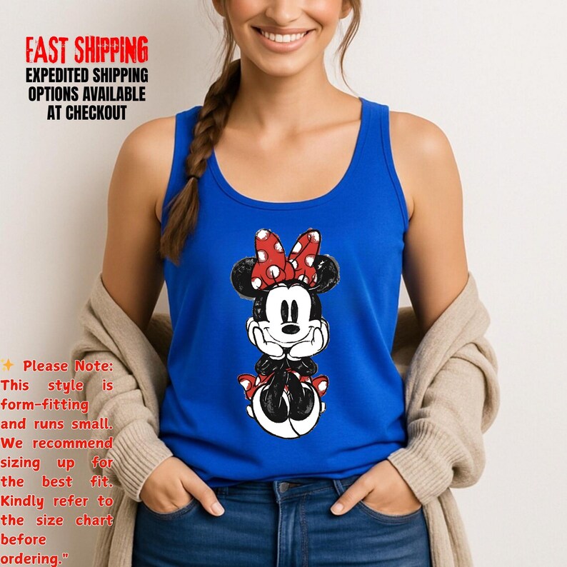 May include: A royal blue tank top featuring a Minnie Mouse graphic. The graphic shows Minnie Mouse with a red polka dot bow, black ears, and a black and white outfit. The tank top is sleeveless and made of a soft material.