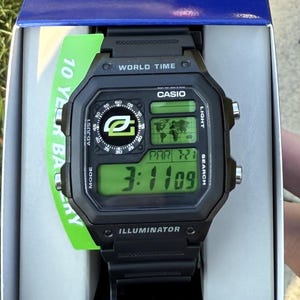 May include: Black Casio digital watch with a rectangular face. The watch displays the time, date, and world time functions on a green digital screen. The watch has the text "WORLD TIME", "CASIO", and "ILLUMINATOR" printed on the face.