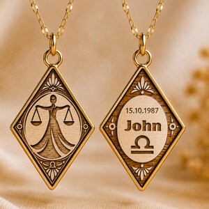 Könnte beinhalten: Zwei goldfarbene Waage-Sternzeichen-Halsketten. Ein Anhänger zeigt das Waage-Waage-Symbol, der andere den Namen "John", das Datum "15.10.1987" und das Waage-Symbol. Beide Anhänger sind rautenförmig.