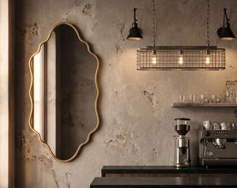 May include: Interior of a cafe featuring a gold-framed mirror, pendant lights, and a coffee bar. The mirror has a wavy edge. The coffee bar includes a coffee grinder, espresso machine, and wooden stools. The walls have a textured, aged appearance.