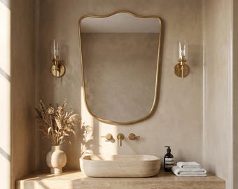 May include: A contemporary bathroom scene featuring a gold-edged mirror, wall sconces, and a stone basin. The vanity unit has a wooden cabinet with horizontal slats and a stone worktop. A vase of dried flowers and white towels complete the decor.