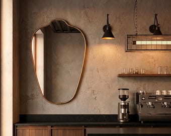 May include: Interior of a coffee shop featuring a gold-framed mirror, dark countertops, and wooden cabinets. The image shows a coffee grinder, espresso machine, and pendant lighting. The walls have a textured finish, creating a warm and welcoming atmosphere.