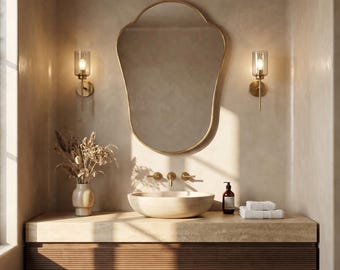 May include: A contemporary bathroom interior featuring a gold-framed mirror and wall sconces. The vanity unit has a stone countertop, a vessel sink, and a dark wood cabinet. A vase of dried flowers and a soap dispenser are also visible.