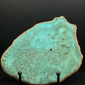 May include: A flat, irregularly shaped slab with a textured, vibrant turquoise-green surface and a smooth, reddish-brown copper edge. The piece features a porous, organic pattern across its face, displaying natural variations in color and depth.