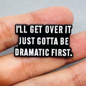 Può includere: Spilla in smalto nero con testo bianco che recita "I'll get over it just gotta be dramatic first."