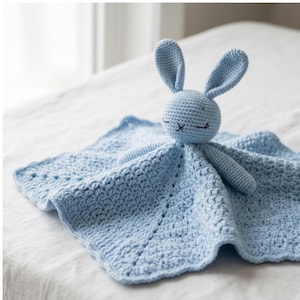 Puede incluir: Una manta de seguridad de crochet azul claro con un conejito. El conejito tiene orejas largas y ojos cerrados. La manta es cuadrada con un borde festoneado. El juguete blando está diseñado para bebés y niños pequeños.
