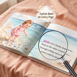 Puede incluir: Un libro infantil abierto con una ilustraci&oacute;n en acuarela de un ni&ntilde;o peque&ntilde;o con vestido rosa en una playa. Una lupa enfoca el texto: Amelia loves Daddy deeper than the ocean blue, deep as the water stretching below.