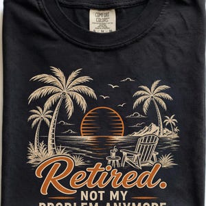 Op de afbeelding: Een zwart t-shirt met een afbeelding van een strandscène met palmbomen, een zonsondergang, een ligstoel en een klein tafeltje met een drankje. De tekst luidt: "Retired. NOT MY PROBLEM ANYMORE." Comfort Colors label in de nek.
